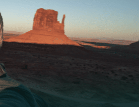 Two Utah singles smiling and taking a selfie while dating with Utah desert scenery in the background.