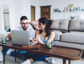 Young couple sitting on a sofa looking at a laptop.