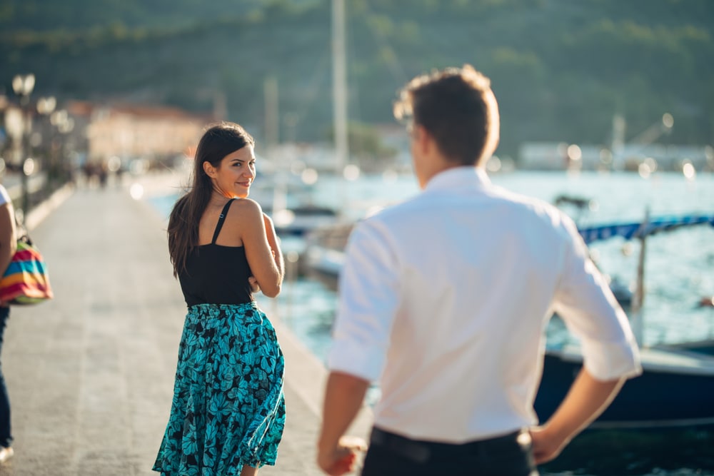 Attractive young woman looking back over her shoulder at a man.