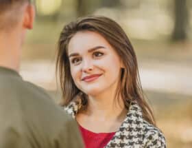 A smiling young woman looking at a man who is facing away from the camera.