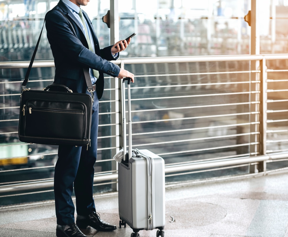 Business man in airport looking at cellphone