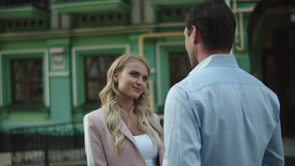 Blonde woman talking to a man in a blue shirt.