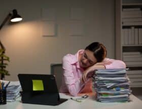 Women sleeping at her desk on a stack of papers.